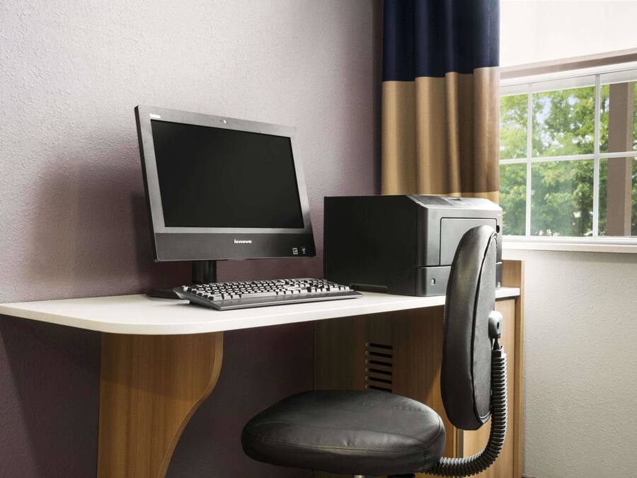 A computer desk with a monitor, keyboard, and printer.