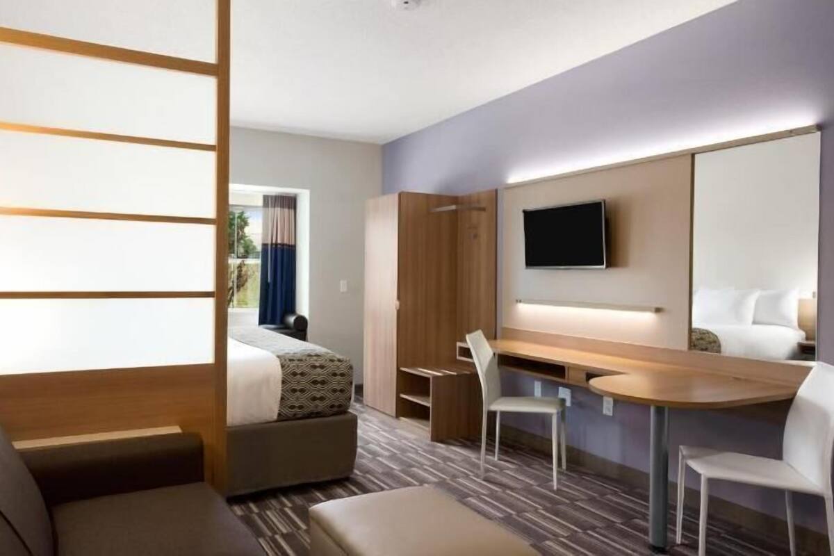 Une chambre d’hôtel équipée d’un canapé, d’un lit, d’un bureau, d’une chaise, d’une télévision et d’un miroir.