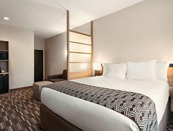 Una habitación de hotel con una cama grande, una mesita de noche, un armario y una alfombra estampada.