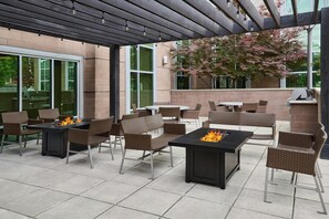 An outdoor patio with tables and chairs, a fire feature, and a pergola. - TownePlace Suites Springfield (Springfield)