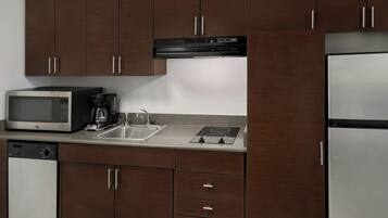 A kitchen with dark wooden cabinets, a stainless steel refrigerator, a microwave, a coffee maker, and a dishwasher.