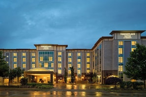 Un hotel con un letrero destacado que dice 'TOWNEPLACE SUITES BY HARRIOTT', que presenta una fachada simétrica con ventanas amplias y una entrada central.