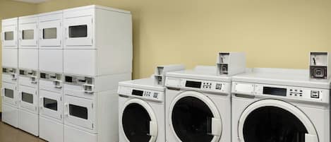 A laundry facility with multiple washing machines and dryers, arranged in rows.