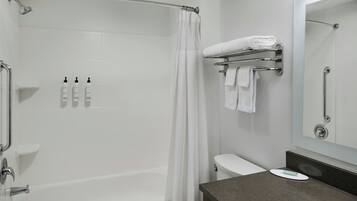 Une salle de bain moderne équipée d’une douche, de toilettes et d’un meuble-lavabo avec un miroir.