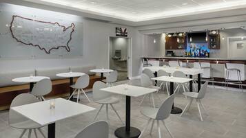 A modern restaurant with white tables and chairs, a bar area, and a large wall map.