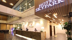 Zona de recepción de hotel con diseño moderno, un mostrador de recepción y un cartel que dice "HOTEL SKYPARK".
