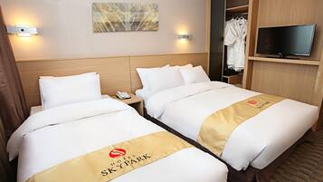 A hotel room with two beds, a TV, a coat rack, and a painting on the wall.