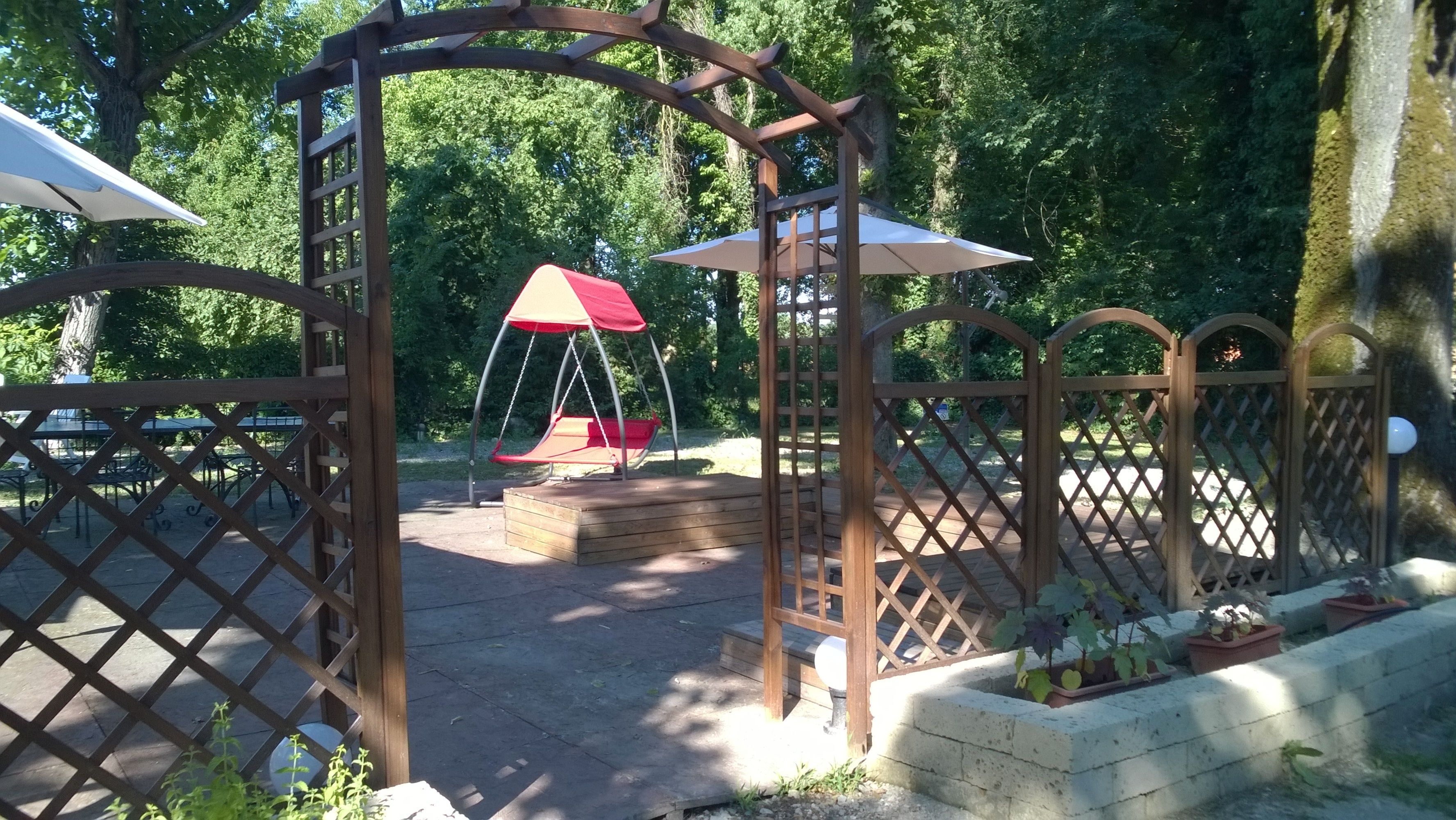 A wooden pergola with a swing set and a covered seating area.