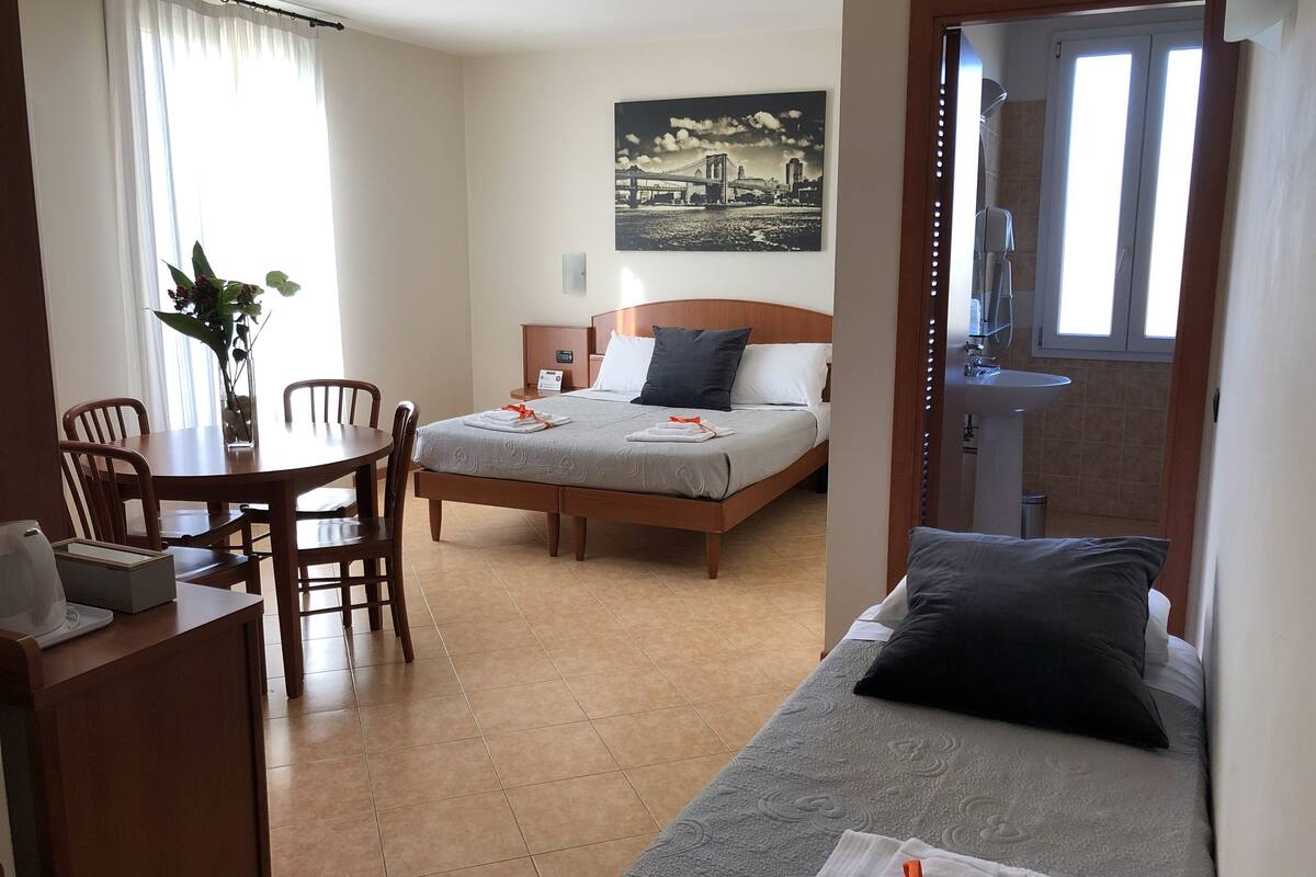 Ein Hotelzimmer mit Bett, Schreibtisch, Stuhl, Esstisch und Bad.