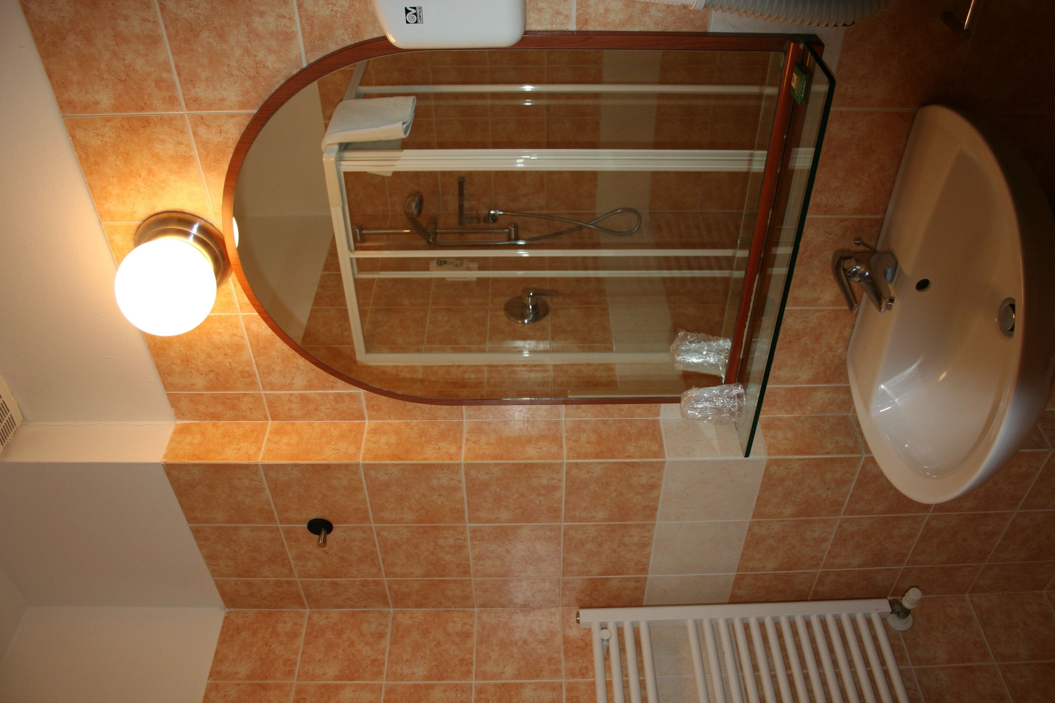 Une salle de bain avec une douche à parois de verre, un lavabo blanc et un porte-serviettes.