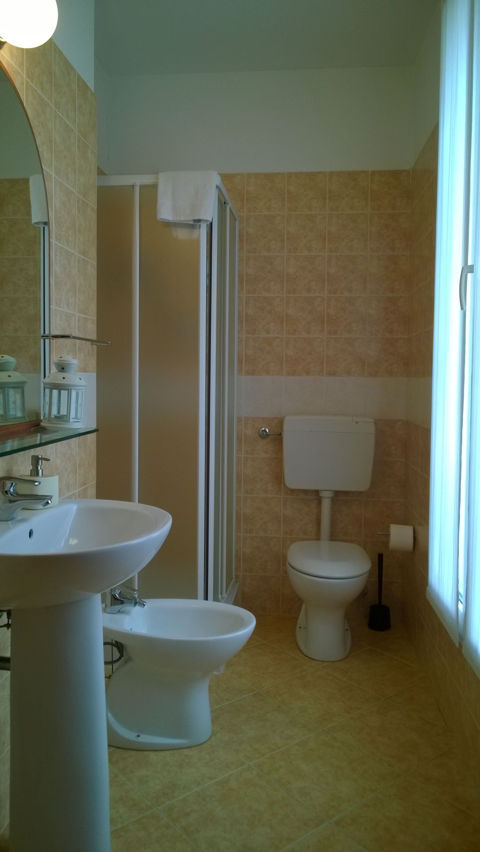 A bathroom with a sink, bidet, toilet, and a glass shower enclosure.