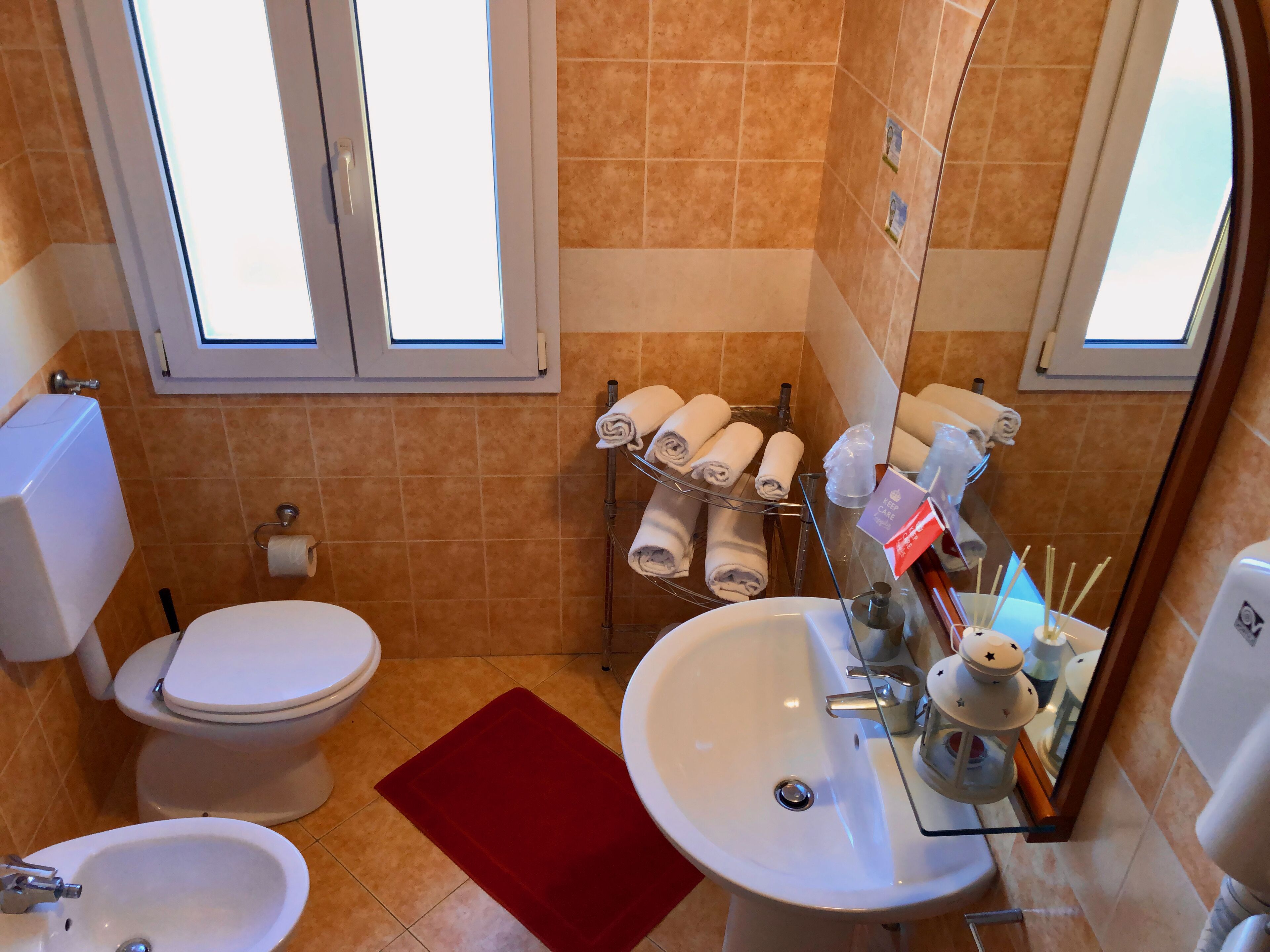 A bathroom with a toilet, bidet, sink, and towel rack.