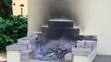 A stone-built outdoor fireplace with a fire, surrounded by steps and a wall.