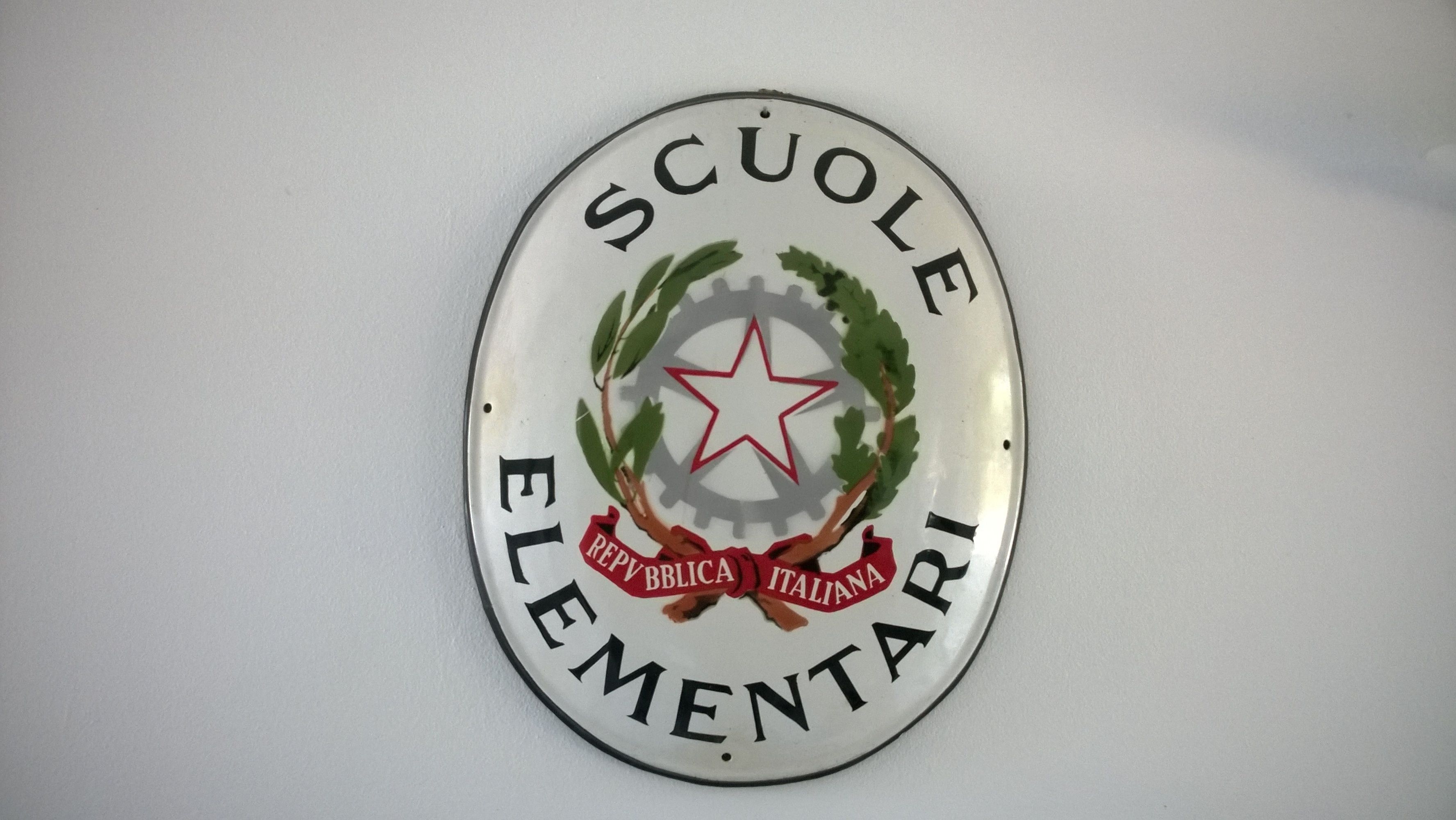 A circular emblem with the text "SCUOLE ELEMENTARI REPUBBLICA ITALIANA" and a star in the center.
