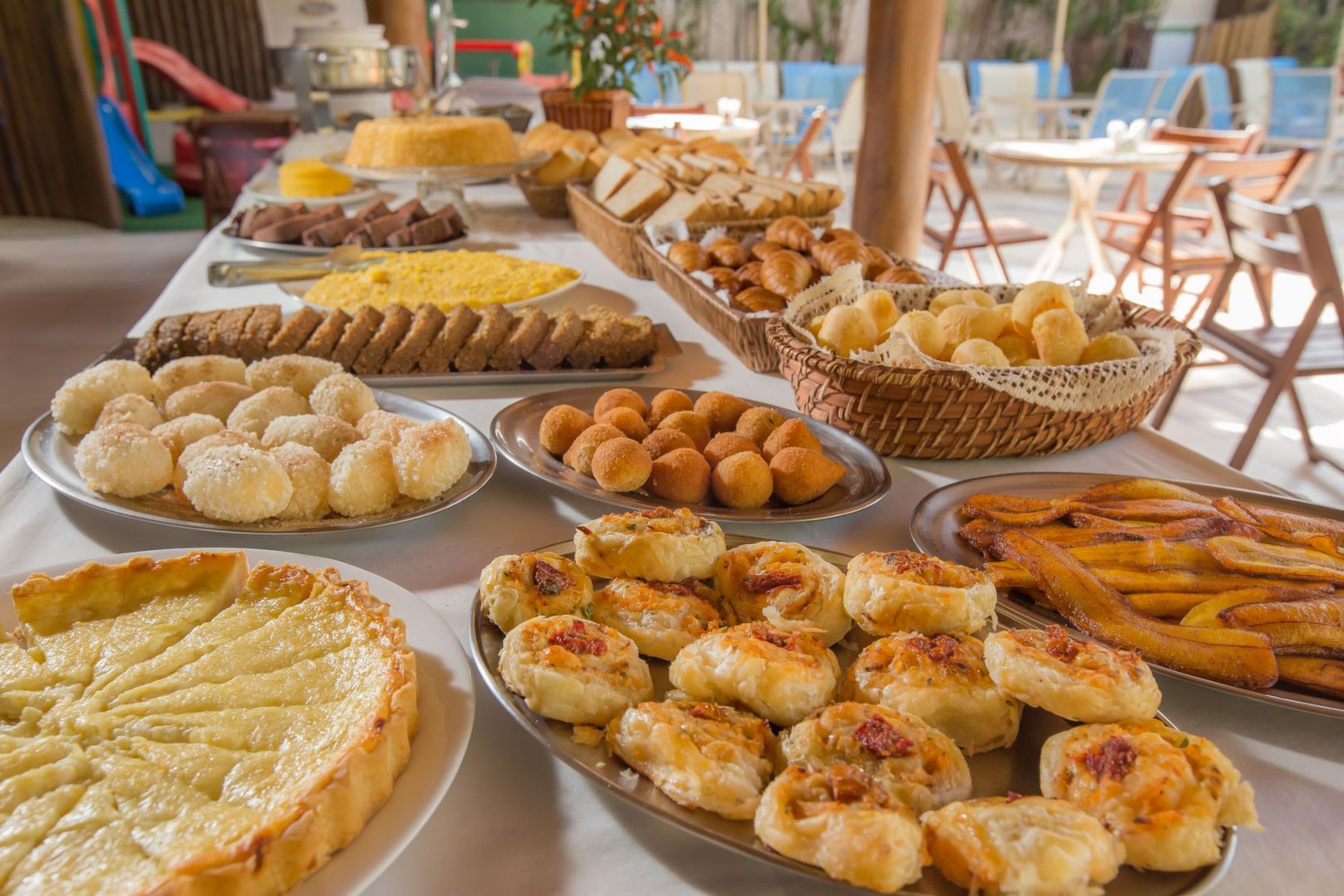 Una mesa de buffet con diversos alimentos, incluyendo pasteles, pan y una tarta grande.