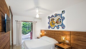 Hotelkamer met houten hoofdeinde, een bed met wit beddengoed, een wandtelevisie, een nachtkastje met lamp en een decoratief mozaïek op de muur.