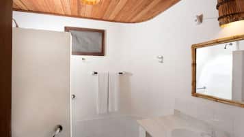Un baño con techo de madera, un lavabo blanco, un espejo y un perchero para toallas.