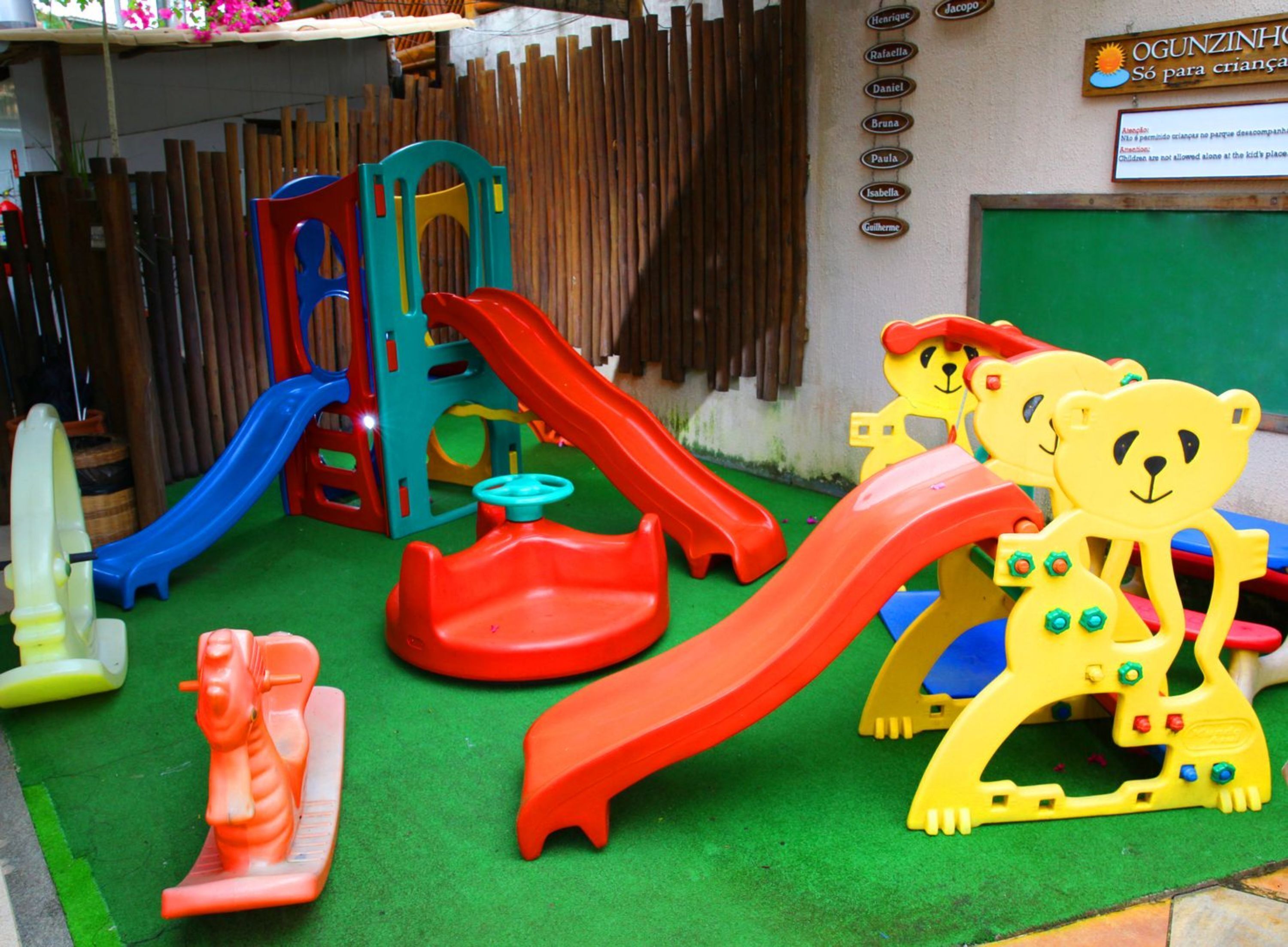 Un espace de jeux pour enfants avec différents toboggans et jouets, notamment un tobogan, une structure d’escalade et des jouets en forme d’ours.