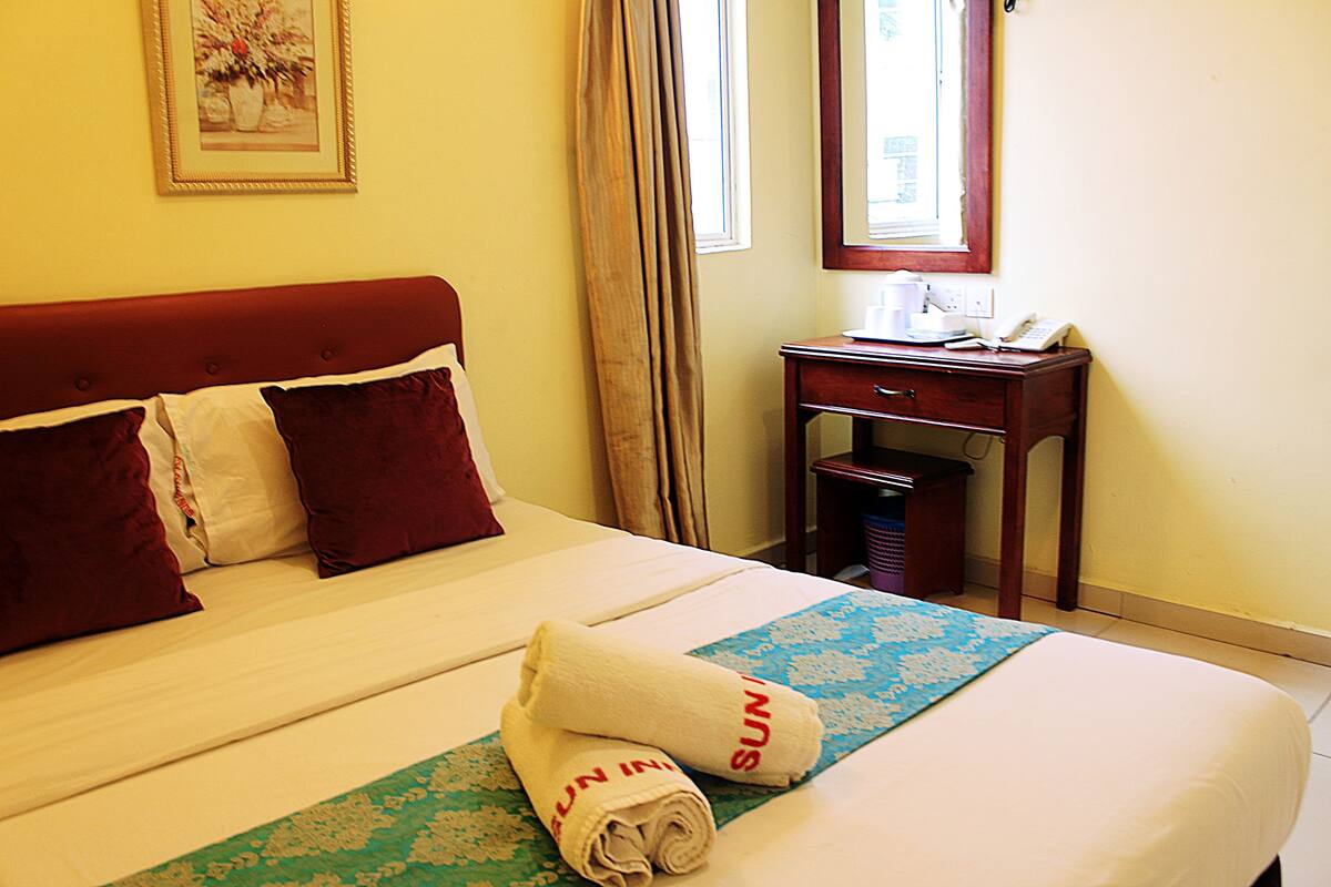 A hotel room with a bed, a desk, and a window.