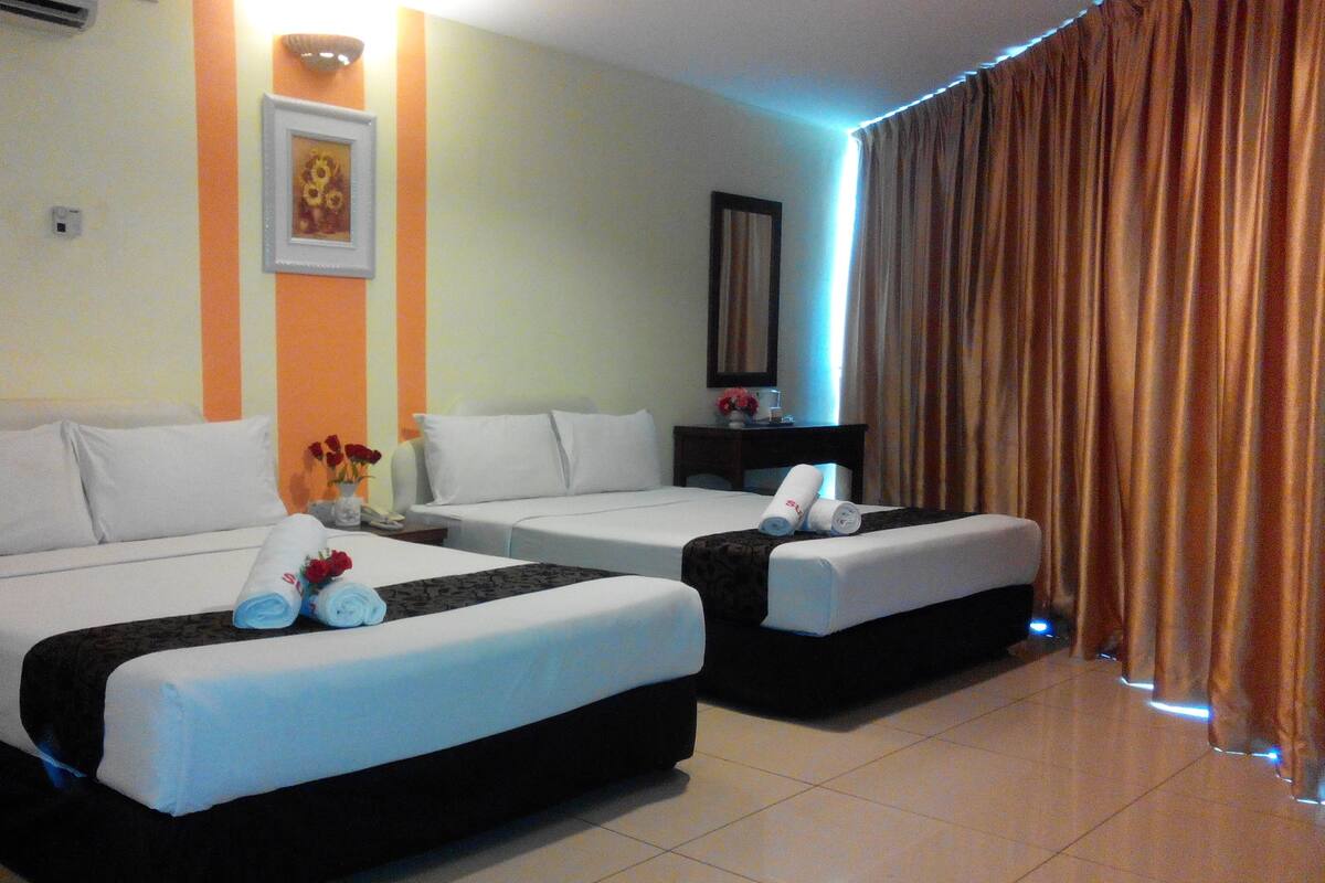 A hotel room with two beds, a nightstand, a mirror, and a window with curtains.