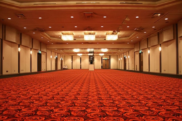 A large, empty hotel room with a red carpet, multiple doors, and chandeliers.