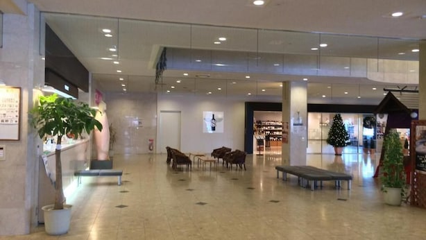 Un hall d’entrée spacieux avec un plafond haut, de nombreux espaces aménagés pour s’asseoir et un sapin de Noël.