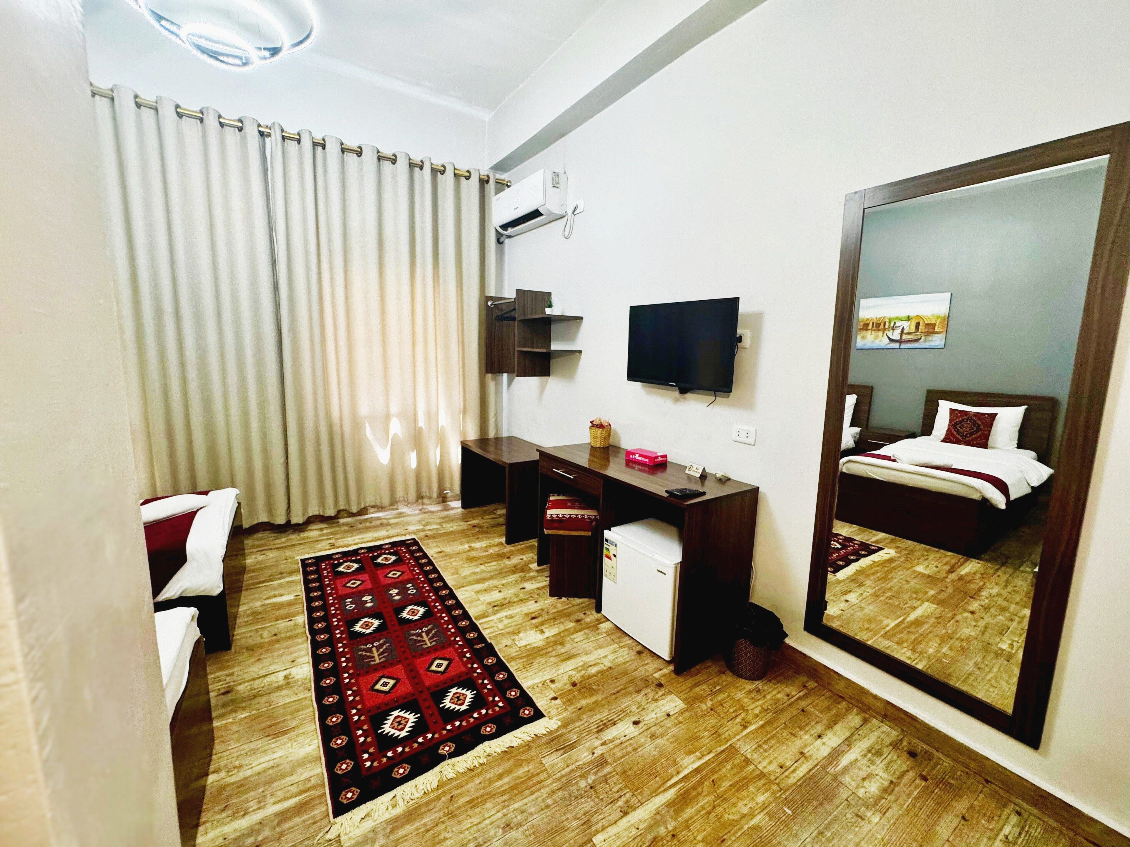 A hotel room with a bed, a desk, a television, and a mirror.