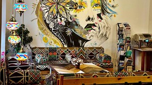 Una habitación con un gran mural, cojines estampados y lámparas colgantes.