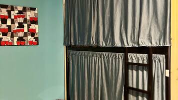 A room with a bunk bed, a patterned wall, and a wooden floor.