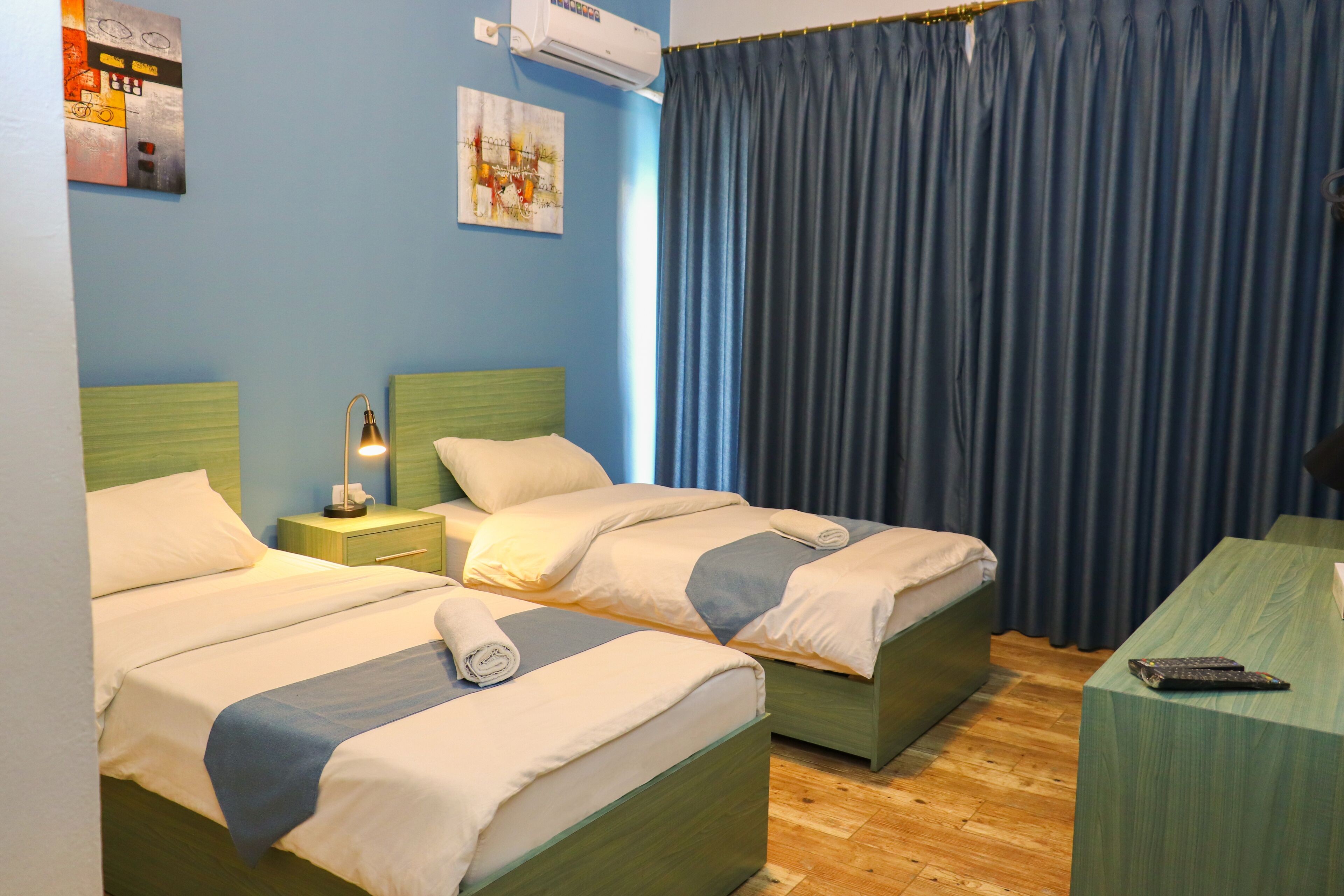 A hotel room with two beds, a desk, and a chair. There are two bedside tables with lamps.