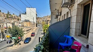 Un balcón con vistas a la calle, una silla azul y una rosa.