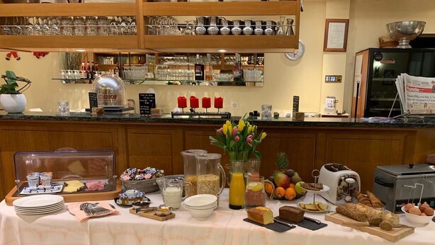 A buffet setup with various food items, a coffee machine, and a newspaper rack. - Auberge Communale (Gilly)