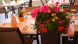 A dining table set with a centerpiece of colorful flowers, neatly arranged cutlery, and a potted plant. - Auberge Communale (Gilly)
