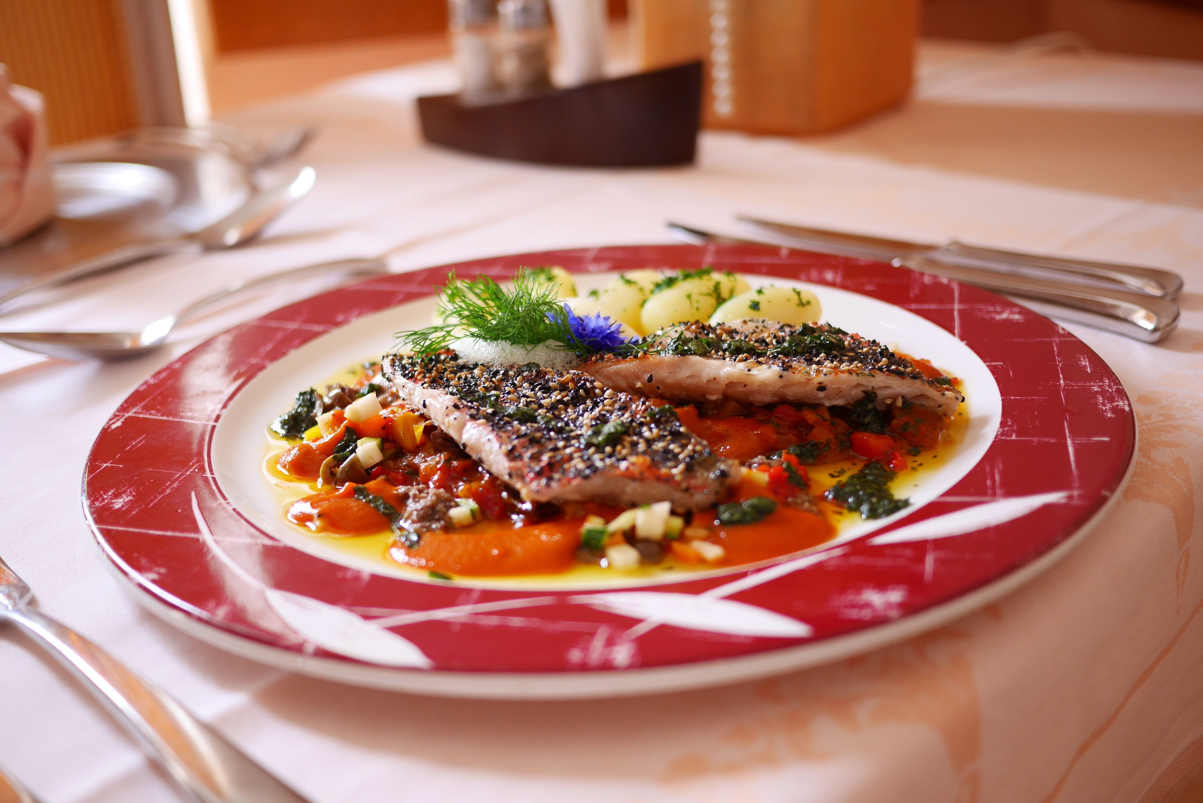 Plat de menjar amb un disseny vermell i blanc, posat sobre una taula amb mantell blanc.