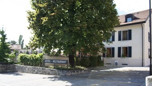 A hotel with a sign indicating it is a restaurant, a parking lot, and a building with a sloped roof. - Auberge Communale (Gilly)