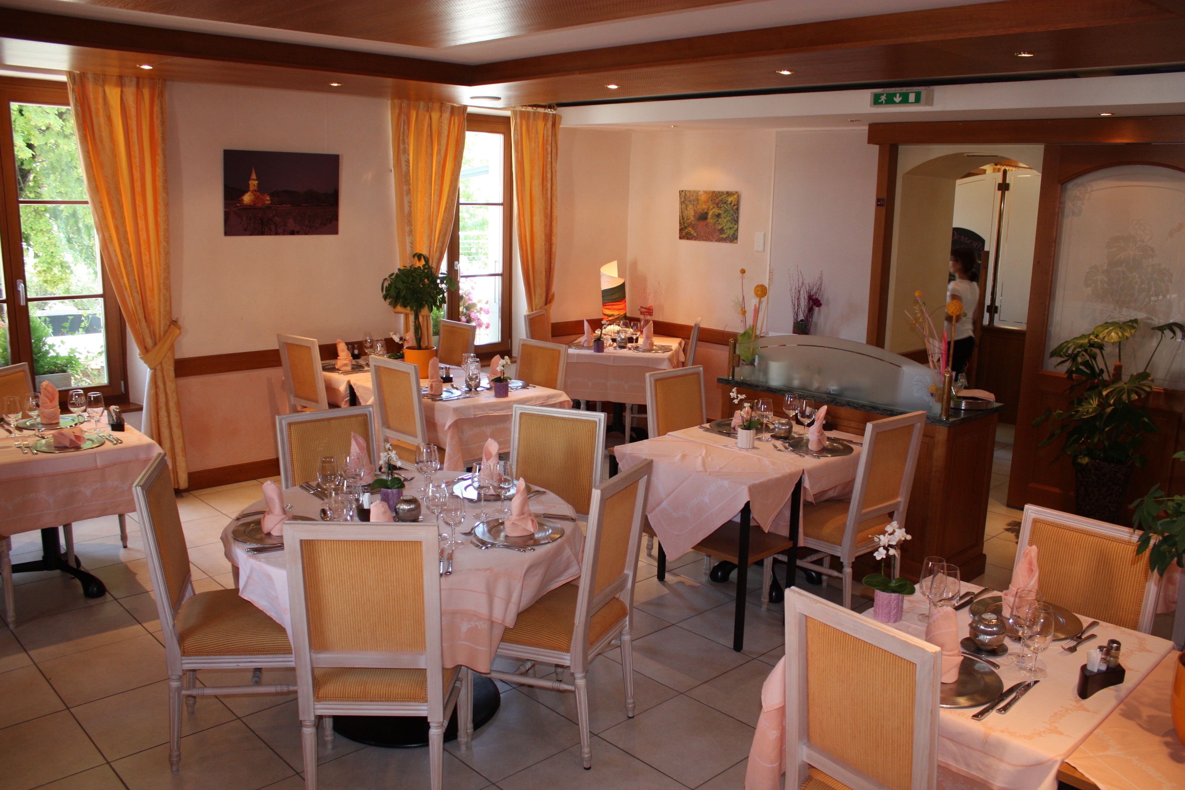 Ein Essbereich mit mehreren gedeckten Tischen für Gäste, inklusive Stühle, Tischdecken und verschiedenen Besteck.