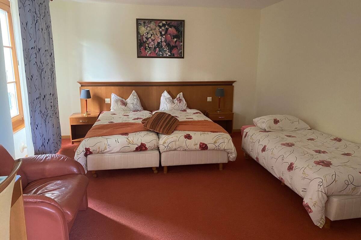 Ett hotellrum med en stor säng, två sängbord med lampor, en liten soffa och en tavla på väggen.