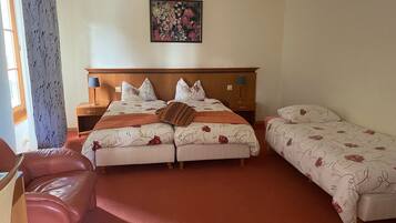 A hotel room with a large bed, two bedside tables with lamps, a small sofa, and a painting on the wall.