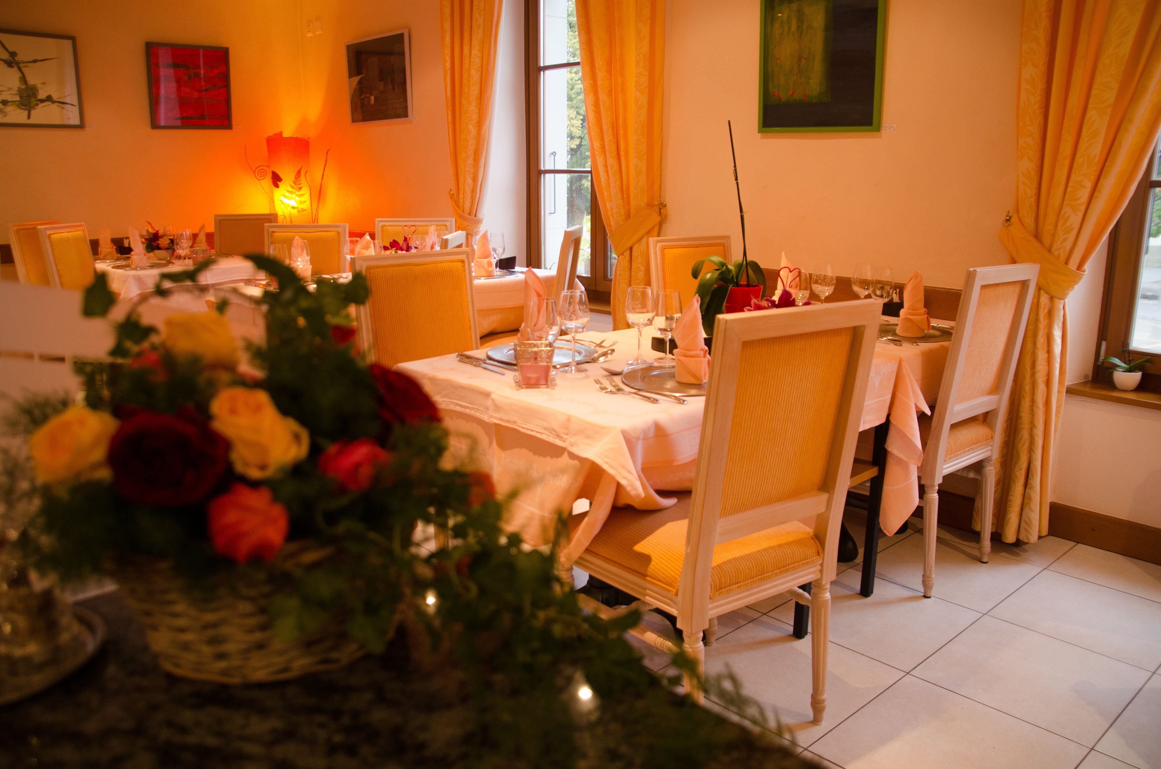 A dining area with tables set for a meal, featuring yellow chairs and white tablecloths.