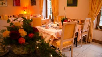 A dining area with tables set for a meal, featuring yellow chairs and white tablecloths.