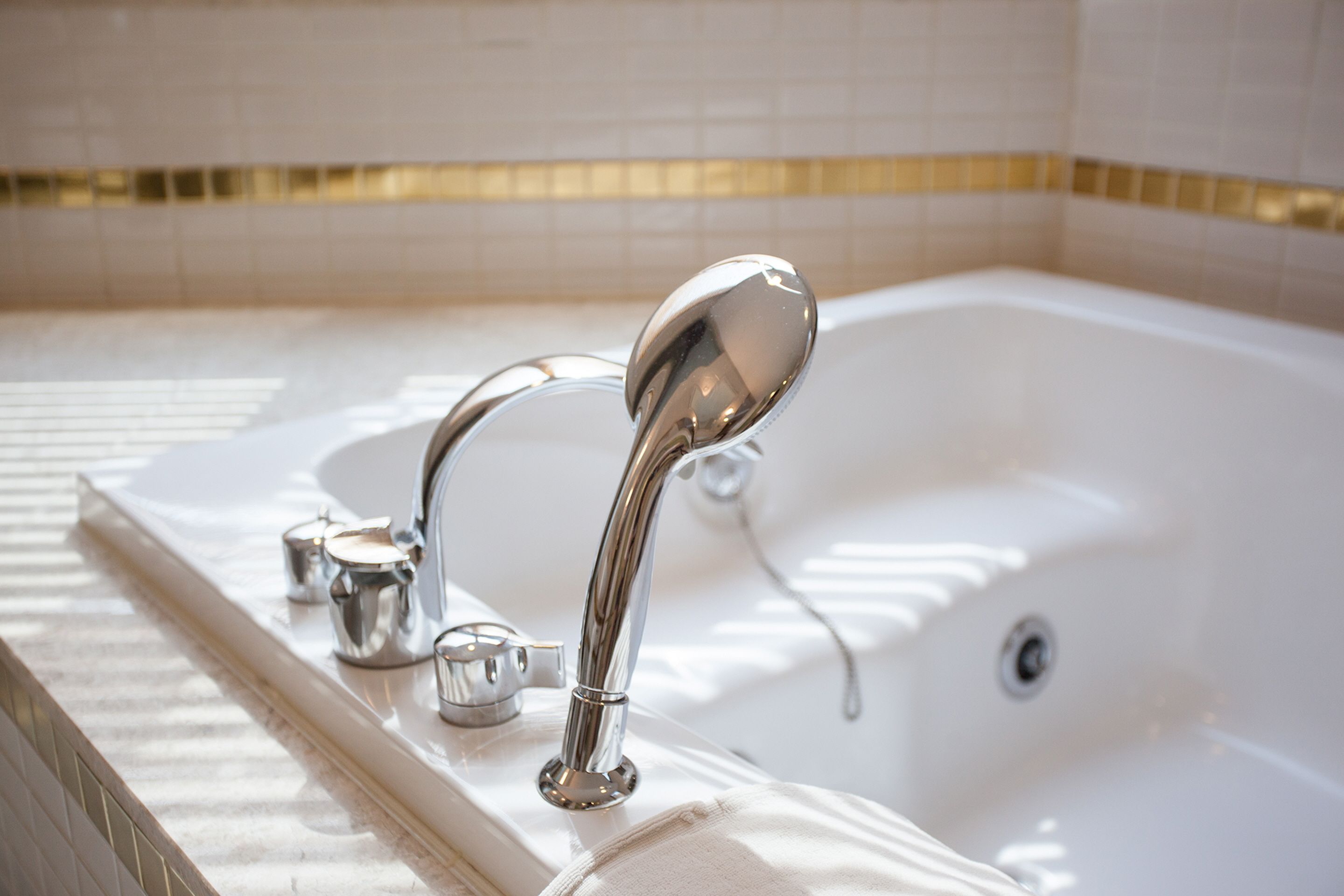 A modern bathroom with a large bathtub, chrome fixtures, and a tiled backsplash.