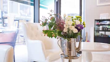 Un interior moderno con un sillón de cuero blanco, un florero de metal y una mesa de vidrio.