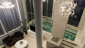 Un intérieur moderne avec un escalier en colimaçon, un espace de vie comprenant un canapé et une table basse, et une grande fenêtre donnant sur une piscine.