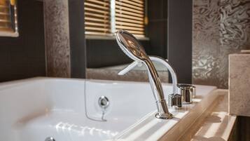 A modern bathroom with a large bathtub, a sleek faucet, and a marble countertop.