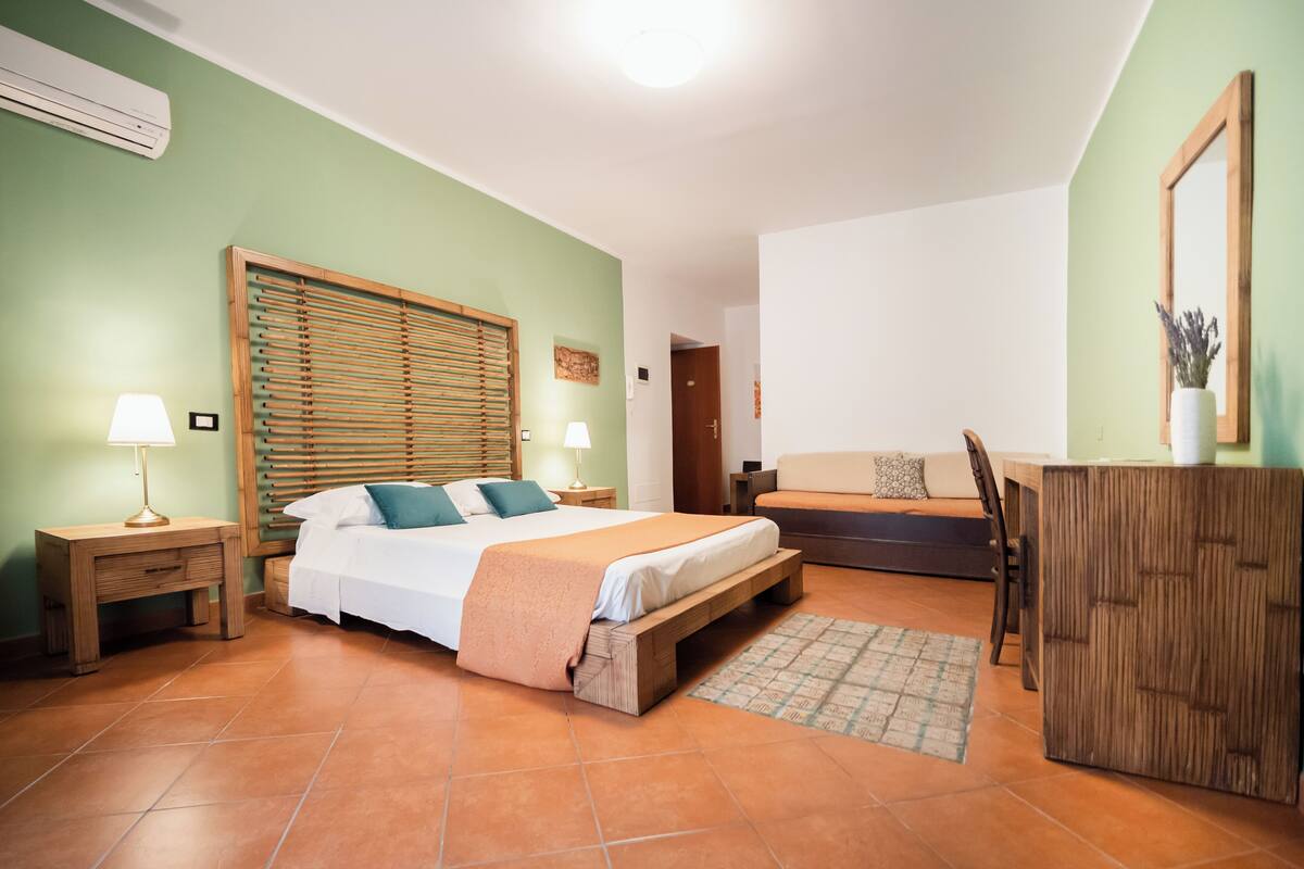 Une chambre à coucher comprenant un lit, des tables de chevet, un banc et une armoire en bois.