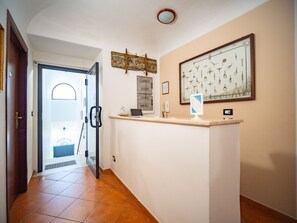 A reception area with a counter, a door leading to another room, and a wall with framed artwork. - Kalamarina Rooms B&B (Palermo)