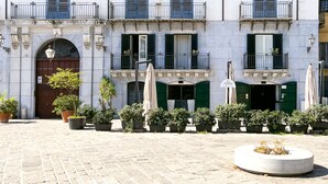 Un edificio con varios balcones, una entrada central con una puerta y plantas en macetas al frente.