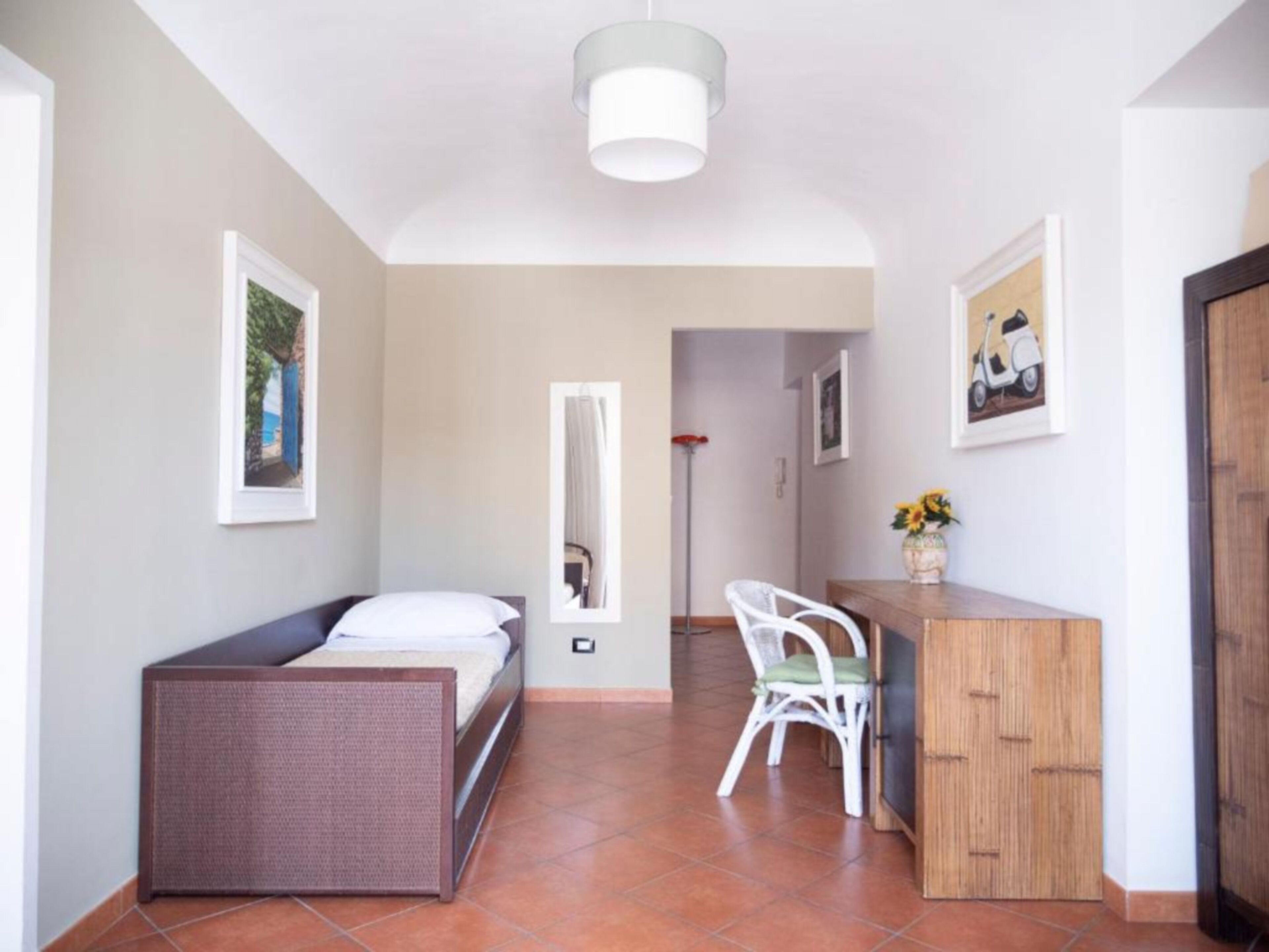 A compact room with a bed, a small desk, a chair, and a cabinet.