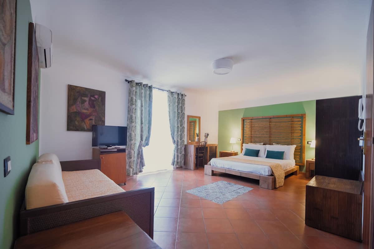 Une chambre d’hôtel comprenant un lit, un bureau, une chaise, une télévision et une salle de bain.