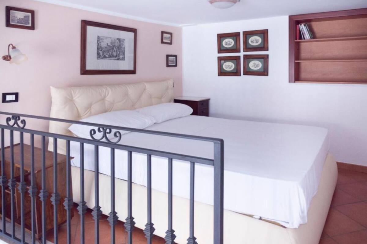 Une chambre à coucher comprenant un lit, une table de chevet, une étagère fixée au mur et un escalier.
